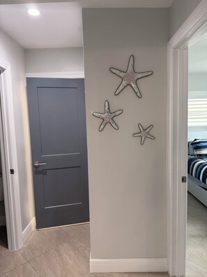 Ein Flur mit einer dunklen Tür, einer hellen Wand und drei Sterndekorationen.