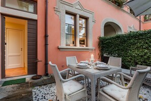 An outdoor dining area with wicker furniture and a table set for four. - Apartment in Lucca With Private Garden (Lucca)