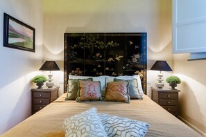 A bedroom with a bed, two bedside tables with lamps, a decorative headboard, and a framed picture on the wall. - Apartment in Lucca With Private Garden (Lucca)
