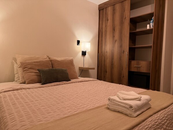 Ein Schlafzimmer mit Bett, Kissen, einer Nachttischlampe und einem Holzschrank.