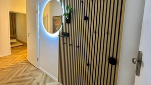 Un pasillo con una puerta de madera, un espejo circular y una planta.