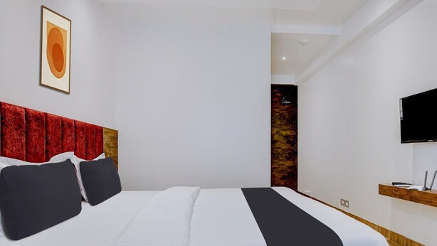 A modern hotel room with a large bed, a mounted television, and a wooden headboard. - Classic Madgaon (Margao)