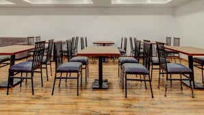 A conference room with multiple tables and chairs, ceiling fans, and recessed lighting. - Classic Madgaon (Margao)