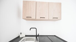 Una cocina con un lavamanos doble, armarios de madera y un grifo negro.