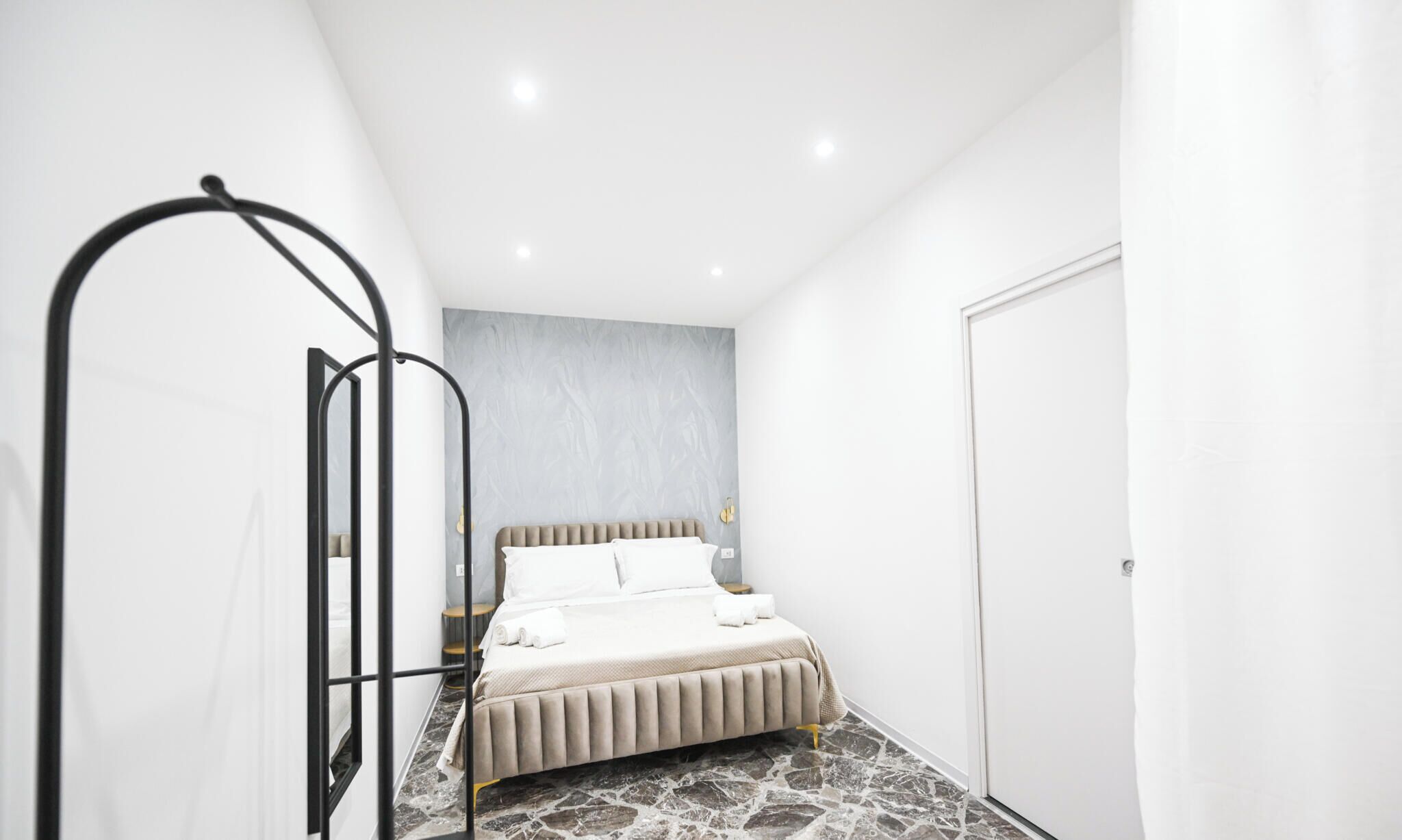 Une chambre à coucher moderne avec un lit, une tête de lit, une table de chevet et une porte.