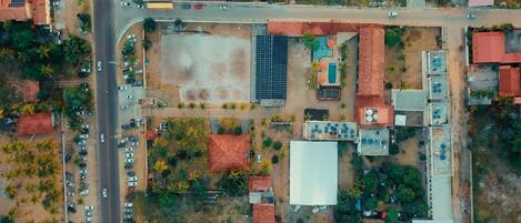 An aerial view of a property with a parking lot, a swimming pool, and several buildings with red roofs.