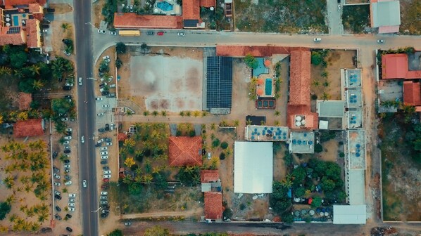An aerial view of a property with a parking lot, a swimming pool, and several buildings with red roofs. - Estância Costa do Sol (Nova Viçosa)