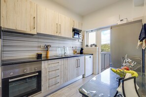 A modern kitchen with wooden cabinets, stainless steel appliances, and a dining area with a table and chairs. - Golden Grandfather's Corner (Albufeira)