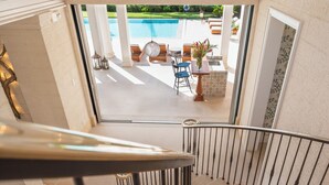 A view from a balcony to a pool area with outdoor seating and a view of the pool. - Villa Tamarindo - by Zenbreak (Holetown)