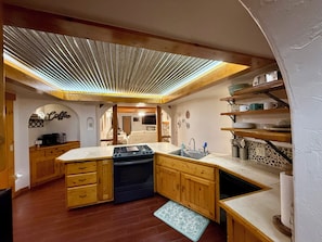A kitchen with wooden cabinets, a built-in oven, a sink, and a ceiling skylight.