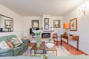 Ein Wohnzimmer mit Sofa, Couchtisch, Kamin, Fernseher und gerahmten Bildern an der Wand.