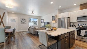 A modern kitchen with a central island, stainless steel appliances, and a dining area with a sofa and table. - Newly Listed Dog Friendly Townhouse Near Downtown Whitefish (Whitefish)