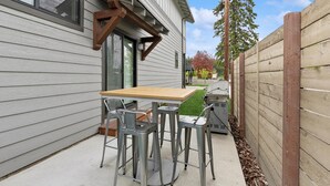 A patio with a table and chairs, a grill, and a wooden fence. - Newly Listed Dog Friendly Townhouse Near Downtown Whitefish (Whitefish)