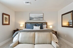 A bedroom with a bed, bedside lamps, a headboard, a framed picture, a mirror, and a chair. - Newly Listed Dog Friendly Townhouse Near Downtown Whitefish (Whitefish)