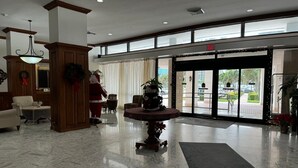 Un vestíbulo con piso de mármol, un árbol de Navidad, una chimenea y un amplio ventanal.