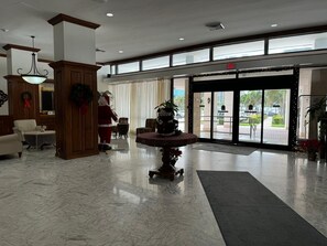 Eine Lobby mit Marmorboden, Weihnachtstannen, Kamin und großem Fenster.