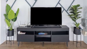 A modern living room with a flat-screen TV, dark wooden flooring, and a geometric-patterned wall. - Modern retreat close to Trinidad's best sites. (Port of Spain)