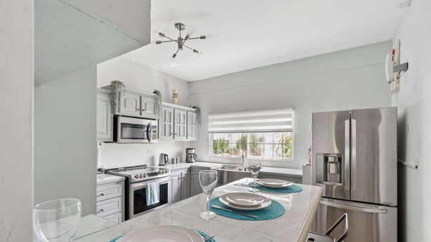 A modern kitchen with a central island, stainless steel appliances, and a view to the outside. - Modern retreat close to Trinidad's best sites. (Port of Spain)
