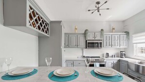 A modern kitchen with white cabinets, a built-in microwave, a stove, and a sink. - Modern retreat close to Trinidad's best sites. (Port of Spain)