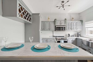A modern kitchen with white cabinets, a built-in microwave, a stove, and a sink. - Modern retreat close to Trinidad's best sites. (Port of Spain)