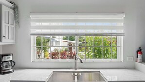 A kitchen with a window, a stainless steel sink, and a coffee maker. - Modern retreat close to Trinidad's best sites. (Port of Spain)
