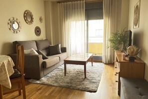 A living room with a sofa, coffee table, and a dining area with a chair and table. - Desconectaengalicia Pinamar with swimming pool, 50m Silgar Beach (Pontevedra)