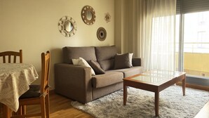 Een woonkamer met een bank, een salontafel, een eettafel met stoelen en decoratieve spiegelwand.