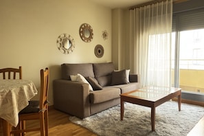 Ein Wohnzimmer mit einer Couch, einem Couchtisch, einem Esstisch mit Stühlen und dekorativen Wandspiegeln.