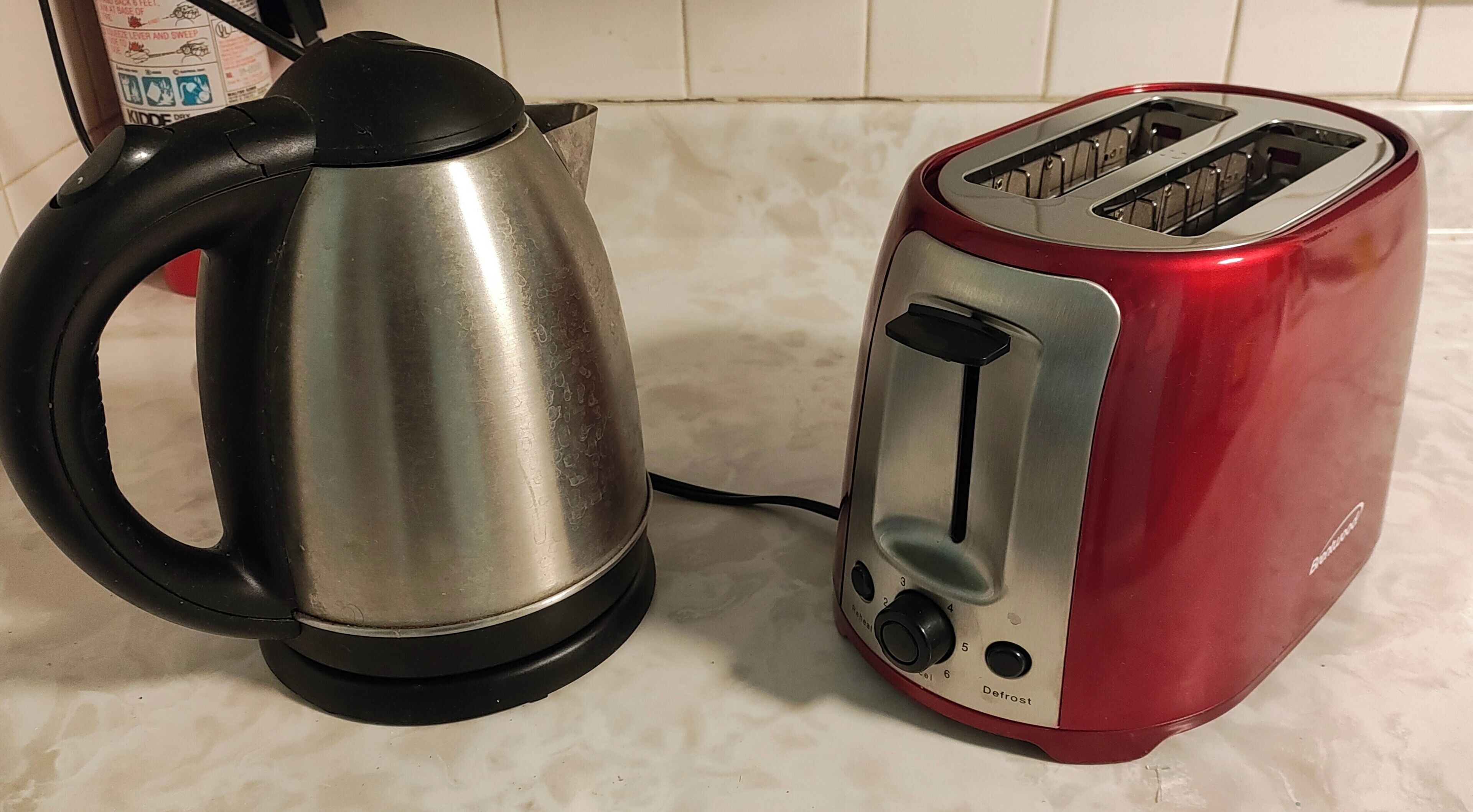 A kettle and a toaster on a countertop.
