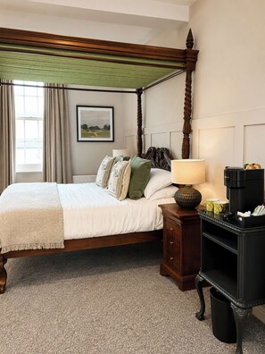 A four-poster bed with a green canopy, a bedside table with a lamp, and a coffee maker. - Raven Suite - 2 | Central Location (Shropshire)
