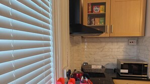 Una cocina con microondas, estufa y un mueble lleno de alimentos.