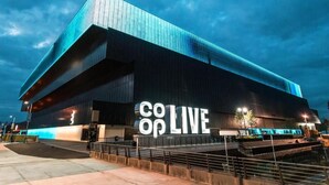 Un edificio moderno con un llamativo letrero 'coop LIVE', techo plano y un amplio acceso.