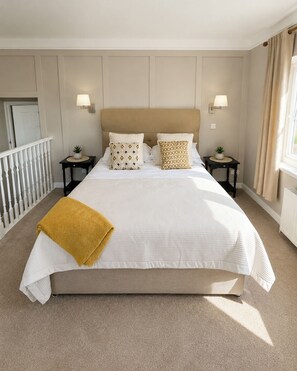 A large bed with a beige headboard, two bedside tables with lamps, and a window with curtains. - Raven Suite - 4 | Central Location (Shropshire)
