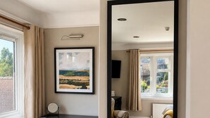 A room with a desk, a chair, a radiator, a window with curtains, and a framed picture on the wall. - Raven Suite - 4 | Central Location (Shropshire)