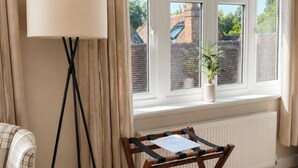 A room with a window, a standing lamp, a small table, and a chair. - Raven Suite - 4 | Central Location (Shropshire)