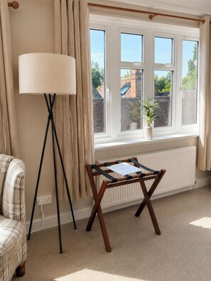 A room with a window, a standing lamp, a small table, and a chair. - Raven Suite - 4 | Central Location (Shropshire)