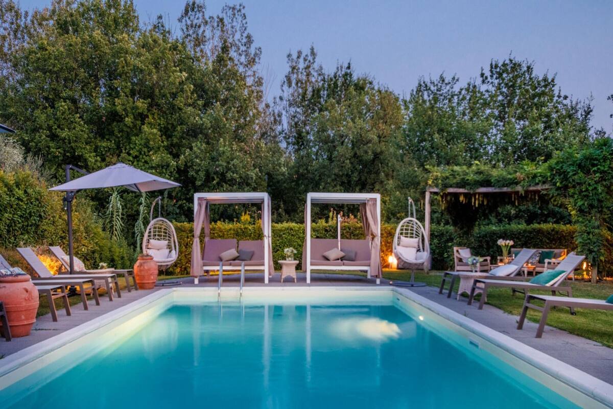 Una piscina con sillones de descanso y una pérgola.