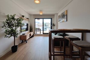 A modern living room with a TV, wooden furniture, a large potted plant, and a view through a glass door. - Desconectaengalicia Mar de Silgar 600m Silgar beach (Pontevedra)