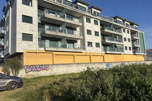 Ein mehrstöckiges Wohngebäude mit Balkonen, einem gelben unteren Abschnitt und Graffiti an der Wand.