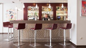Zona de bar con un cantinero, taburetes y una variedad de botellas de licor.