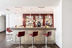 Eine moderne Bar mit Theke, Barhocker und einer Auswahl an Flaschen und Gläsern.