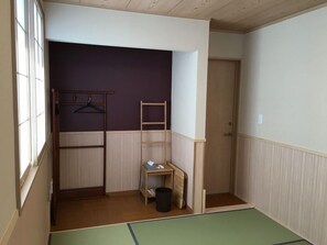A room with a bunk bed, a wooden ladder, a small table with a trash bin, and a door. - Guesthouse Orange Cabin (Fujikawaguchiko)
