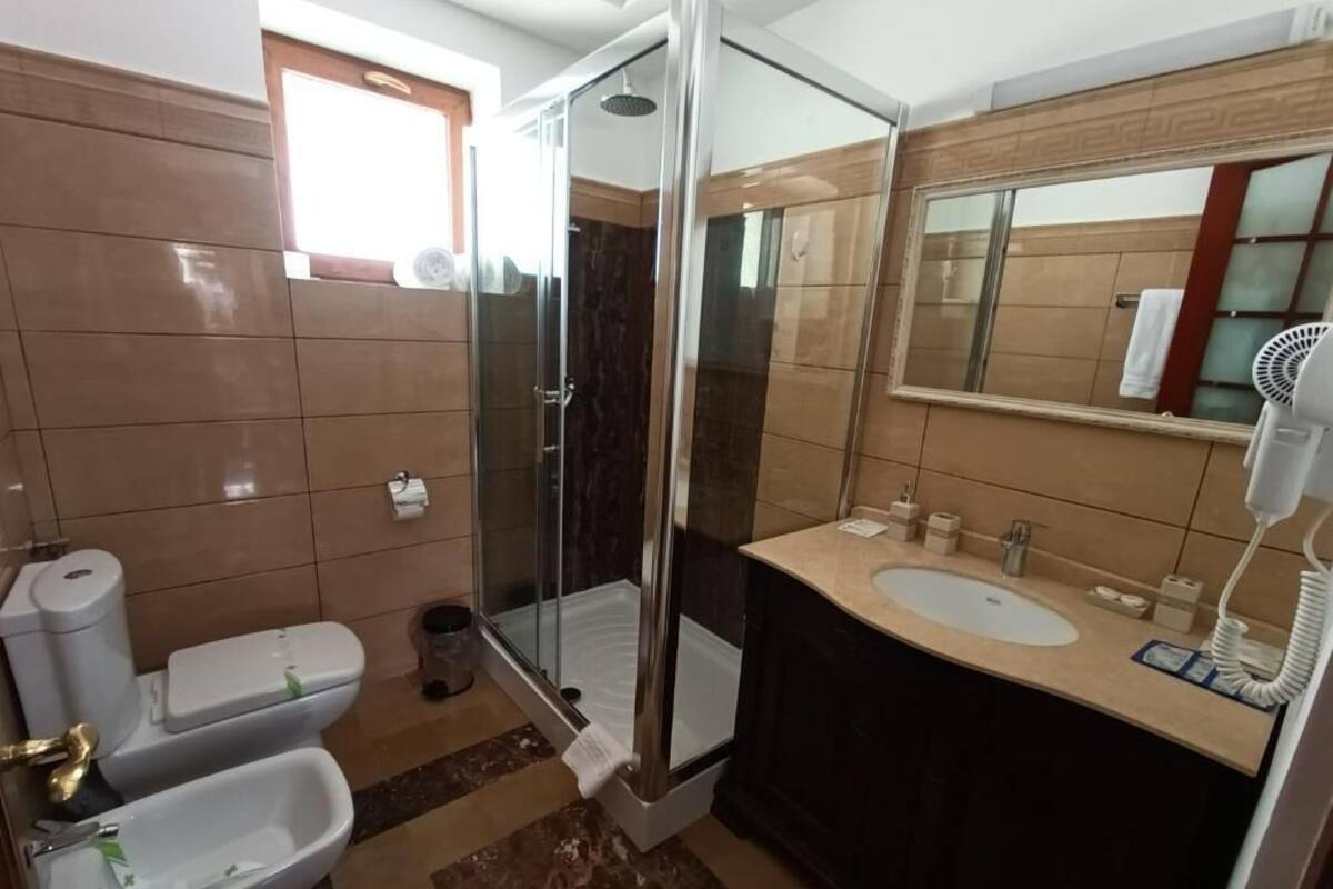 Un baño con ducha de vidrio, lavabo, inodoro y espejo.
