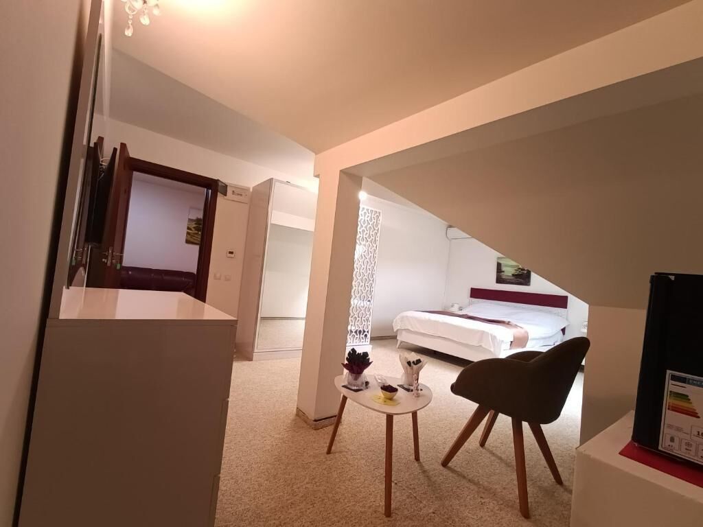 A hotel room with a bed, a small table with a chair, and a TV on a stand.