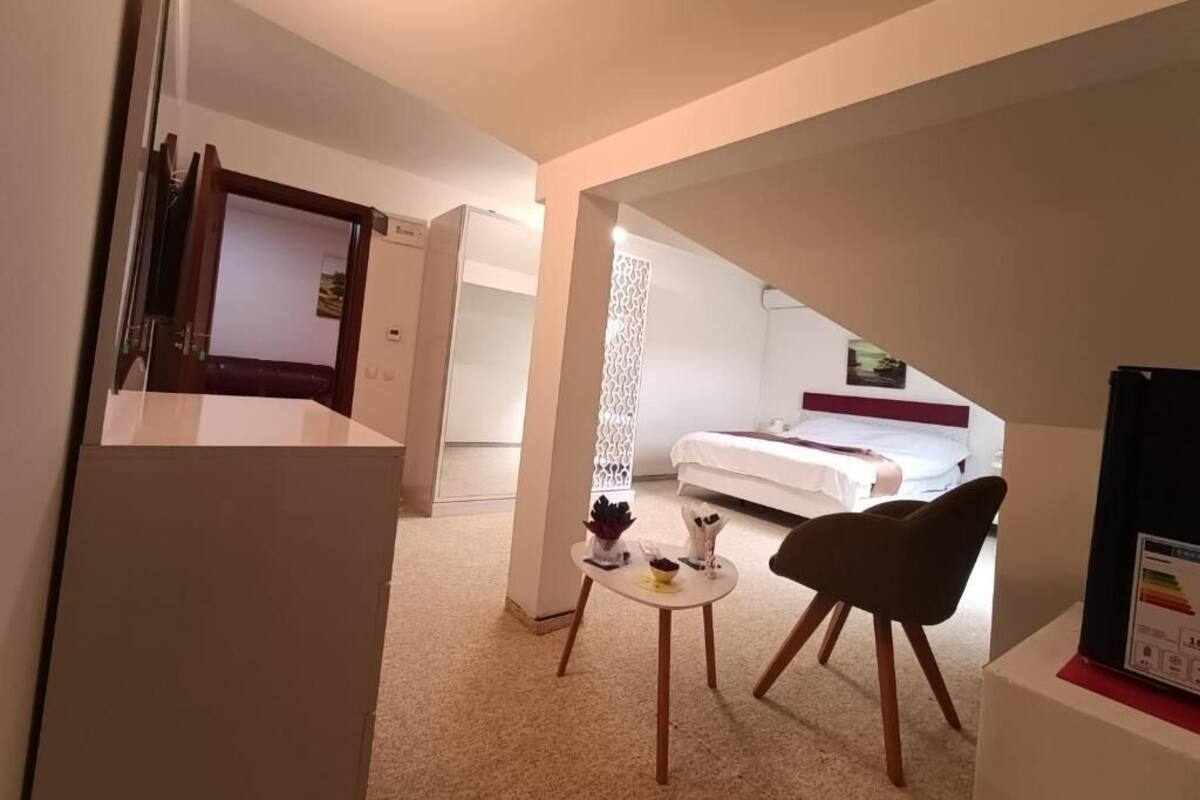 Una habitación de hotel con una cama, una mesita con una silla y un televisor sobre un soporte.