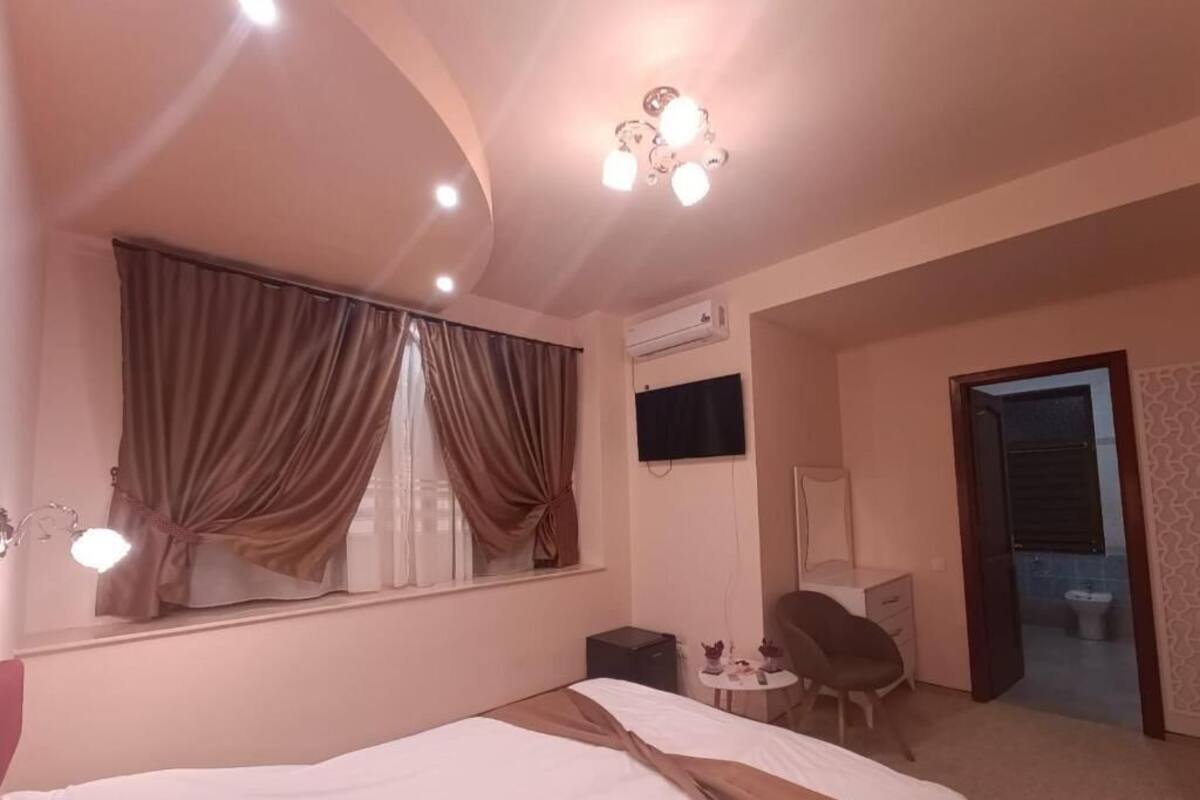 Una habitación de hotel con cama, escritorio, silla, televisión y baño visible a través de una puerta abierta.