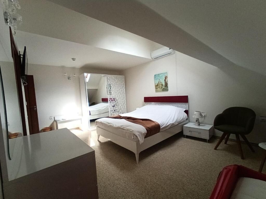 A bedroom with a bed, bedside table, chair, and a desk.