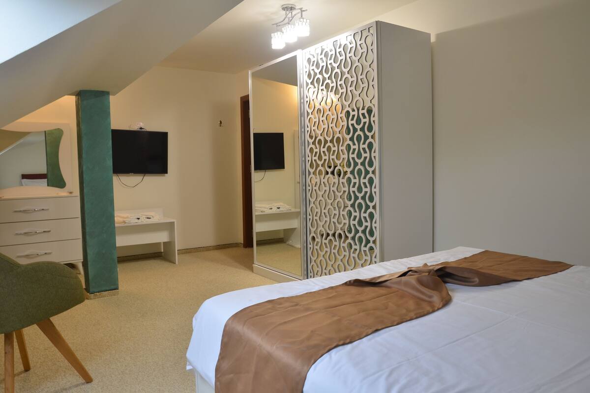 Un dormitorio con cama, cómoda, espejo y televisor en la pared.
