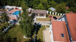 An aerial view of a residential area with a swimming pool, a covered patio, and a red-roofed house. - Virginia Gardens  (Baile Govora)