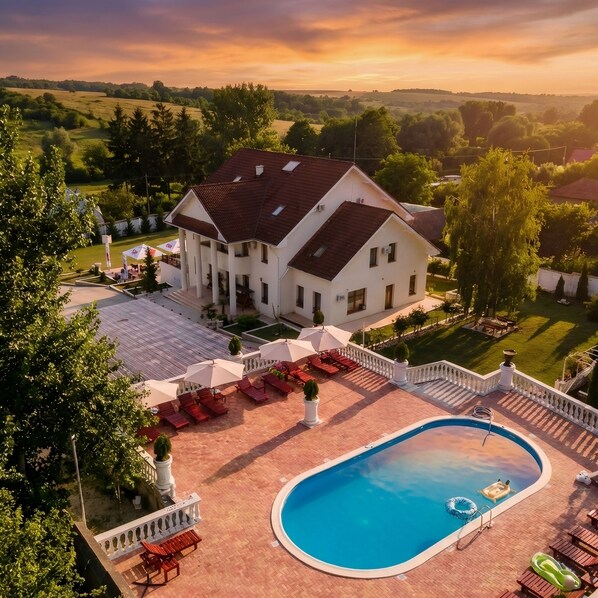 A large house with a swimming pool, outdoor seating, and a view of the surrounding landscape.